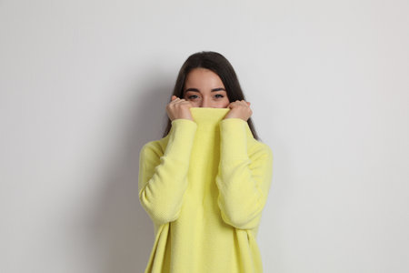Beautiful young woman wearing yellow warm sweater on white backgroundの写真素材