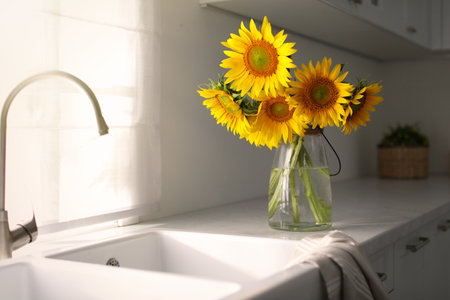 Vase with beautiful yellow sunflowers in the kitchenの写真素材