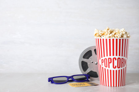 Delicious popcorn, glasses, ticket and tape on light table. Space for textの写真素材