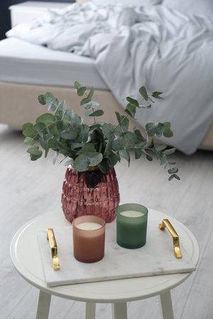 Candles and eucalyptus branches on white table in bedroom. interior elementの写真素材