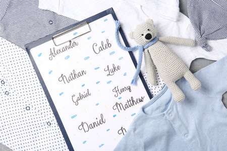 Clipboard with different baby names and toy on child's clothes, top viewの写真素材