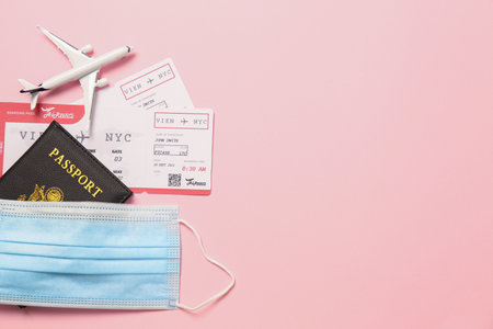 Flat lay composition with passport and protective mask on pink background, space for text. Travel during quarantineの写真素材