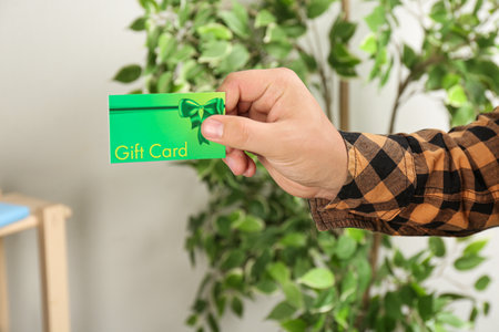 Man with gift card on blurred background, closeupの写真素材