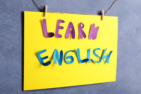 Note with phrase Learn English pinned on thread against gray backgroundの写真素材