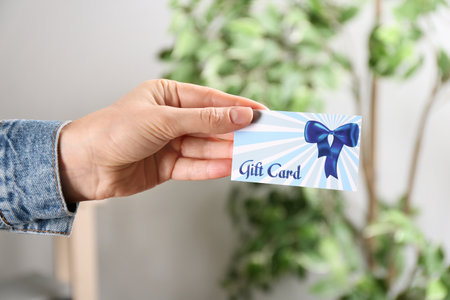 Woman with gift card on blurred background, closeupの写真素材