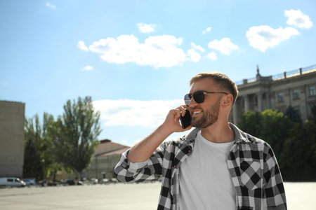 Young man talking on smartphone on city streetの写真素材