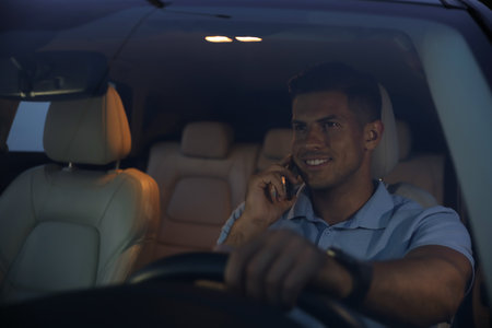 Handsome man talking on phone while driving his modern car