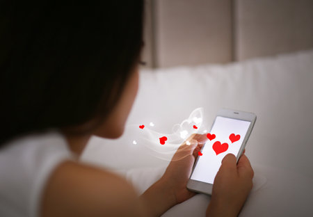 Young woman dating visiting site via smartphone indoorsの写真素材