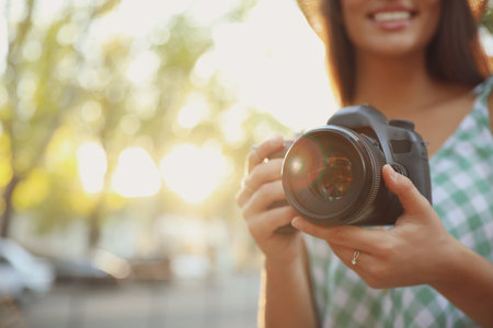 Young photographer with professional camera outdoors, closeup. Space for textの写真素材
