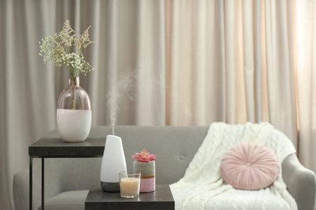 Aroma oil diffuser and candle on table in room