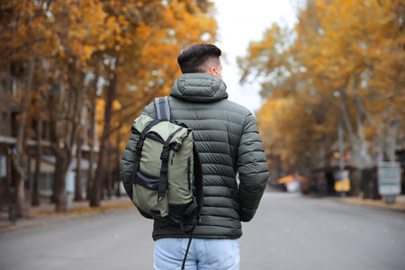 Male tourist with travel backpack on city street, back view. urban tripの写真素材