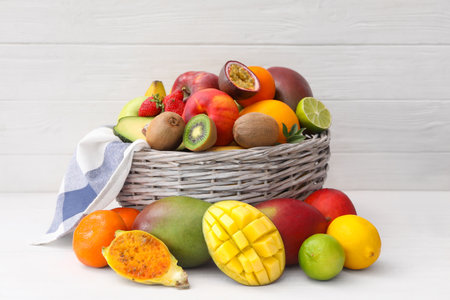 Assortment of fresh exotic fruits in basket on white wooden tableの写真素材