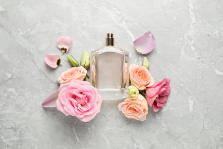 Flat lay composition with bottle of perfume and fresh flowers on light gray marble backgroundの写真素材