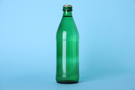 Glass bottle with water on light blue backgroundの写真素材