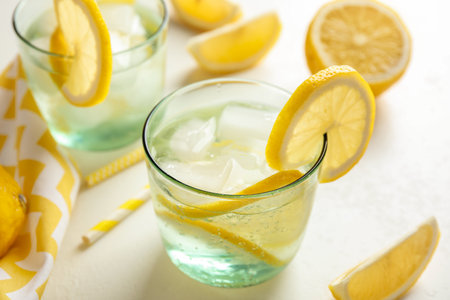 Soda water with lemon slices and ice cubes on white tableの写真素材