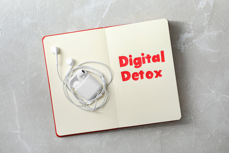 Open notebook with earphones and words DIGITAL DETOX on light gray marble background, top viewの写真素材