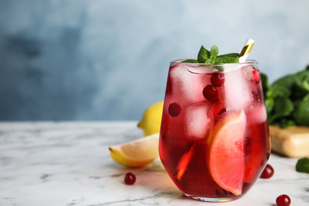 Tasty refreshing cranberry cocktail with mint on white marble table, closeup. Space for textの写真素材