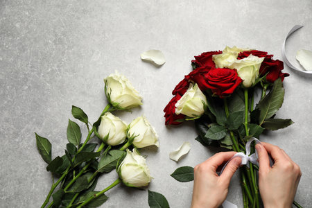 Woman making luxury bouquet of fresh roses at gray table, top viewの写真素材
