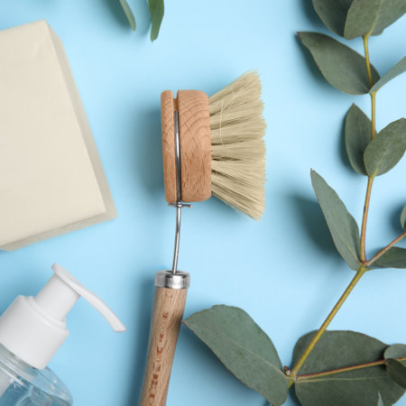 Cleaning supplies for dish washing and eucalyptus branch on light blue background, flat layの写真素材