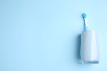 Toothbrush in holder on light blue background, top view. Space for textの写真素材