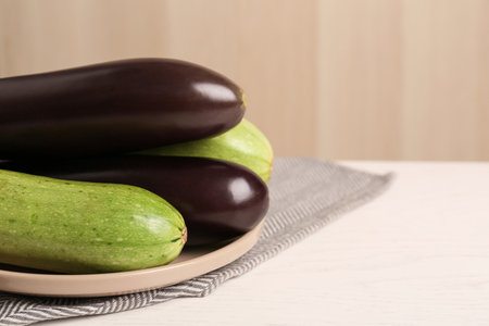 Fresh eggplants and zucchinis on white wooden table, closeup. Space for textの写真素材