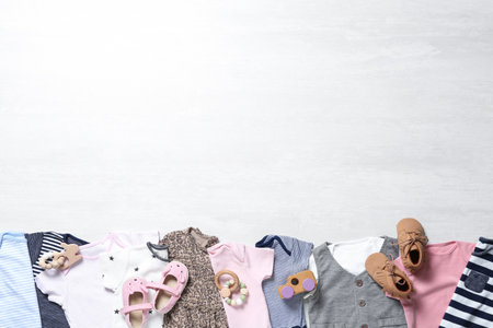 Flat lay composition with cute baby clothes and shoes on white wooden background. Space for textの写真素材