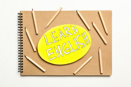 Notepad with phrase Learn English and pencils on white background, top viewの写真素材