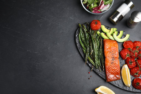 Tasty cooked salmon and vegetables served on black table, flat lay with space for text. Healthy meals from air fryerの写真素材