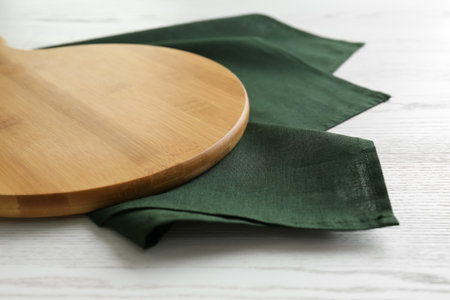 Empty wooden board and green napkin on white table, closeupの写真素材