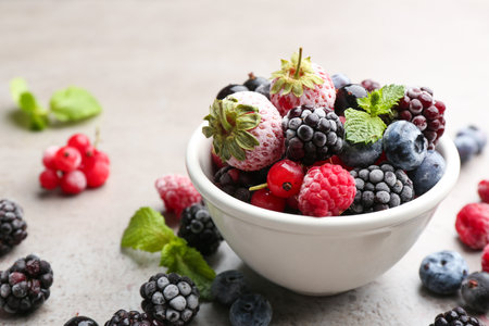Mix of different frozen berries on grey table, closeup. Space for textの写真素材