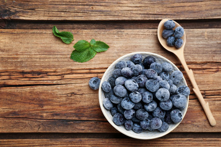 Tasty frozen blueberries on wooden table, flat lay. Space for textの写真素材
