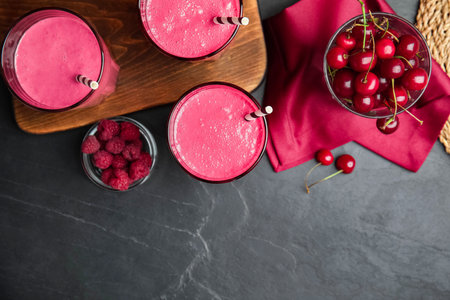 Tasty fresh milk shakes with berries on black table, flat lay. Space for textの写真素材