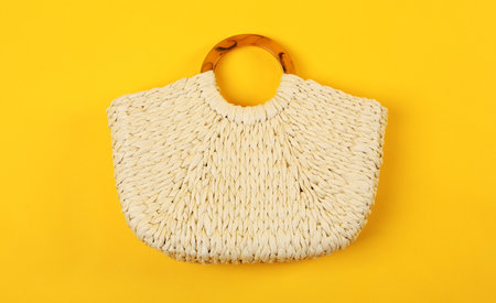 Stylish woman's straw bag on yellow background, top viewの写真素材