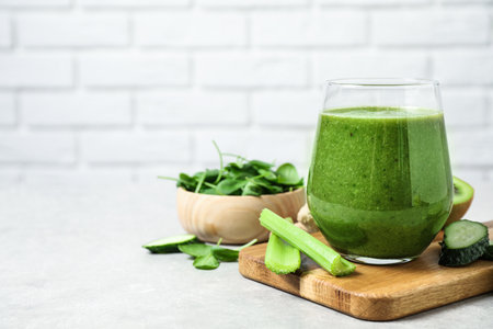 Delicious green juice and fresh ingredients on table against brick wall, space for textの写真素材