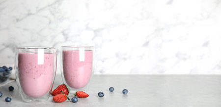 Tasty milk shakes and fresh berries on gray marble table. Space for textの写真素材