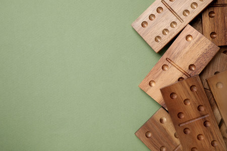Wooden domino tiles on green background, flat lay. Space for textの写真素材