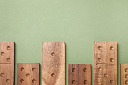 Wooden domino tiles on green background, flat lay. Space for textの写真素材