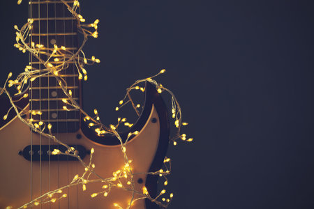 Guitar with festive lights on dark background, space for text. Christmas musicの写真素材