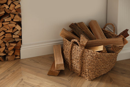 Basket with firewood on floor in roomの写真素材