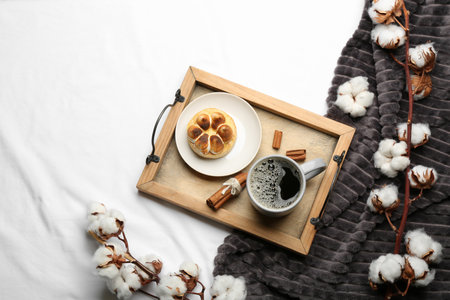 Flat lay composition with hot drink and warm plaid on white bedsheetの写真素材