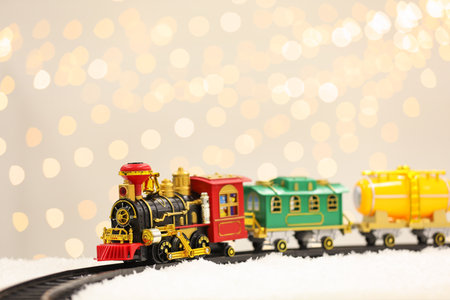 Toy train and railway on snow against Christmas lightsの写真素材