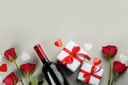 Beautiful gift boxes, roses and wine on grey background, flat lay with space for text. Valentine's day celebrationの写真素材