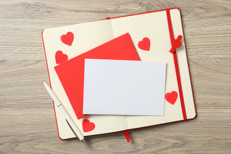Blank card, envelope and notebook on wooden background, top view with space for text. Valentine's Day celebrationの写真素材