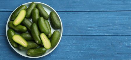 Fresh seedless avocados in ceramic bowl on blue wooden table, top view. Space for textの写真素材