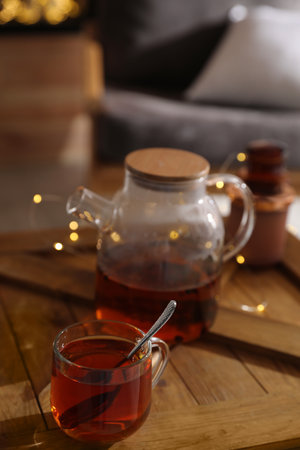 Teapot and cup with hot tea on table indoorsの写真素材
