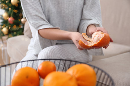 Woman peeling tangerine in room decorated for Christmas, closeupの写真素材