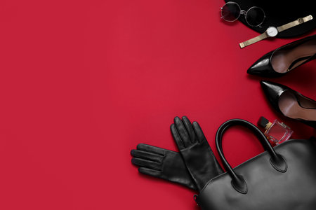 Flat lay composition with stylish black leather gloves, shoes and accessories on red background. Space for textの写真素材