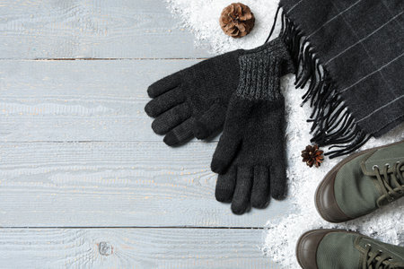 Stylish woolen gloves, scarf, pair of shoes and winter decor on grey wooden table, flat lay. Space for textの写真素材