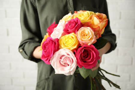 Woman holding luxury bouquet of fresh roses near white brick wall, closeupの写真素材