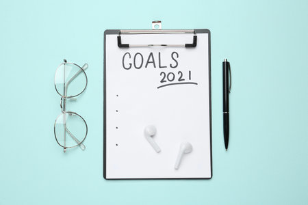 Clipboard with inscription Goals 2021, new year aims. Objects on turquoise background, flat layの写真素材
